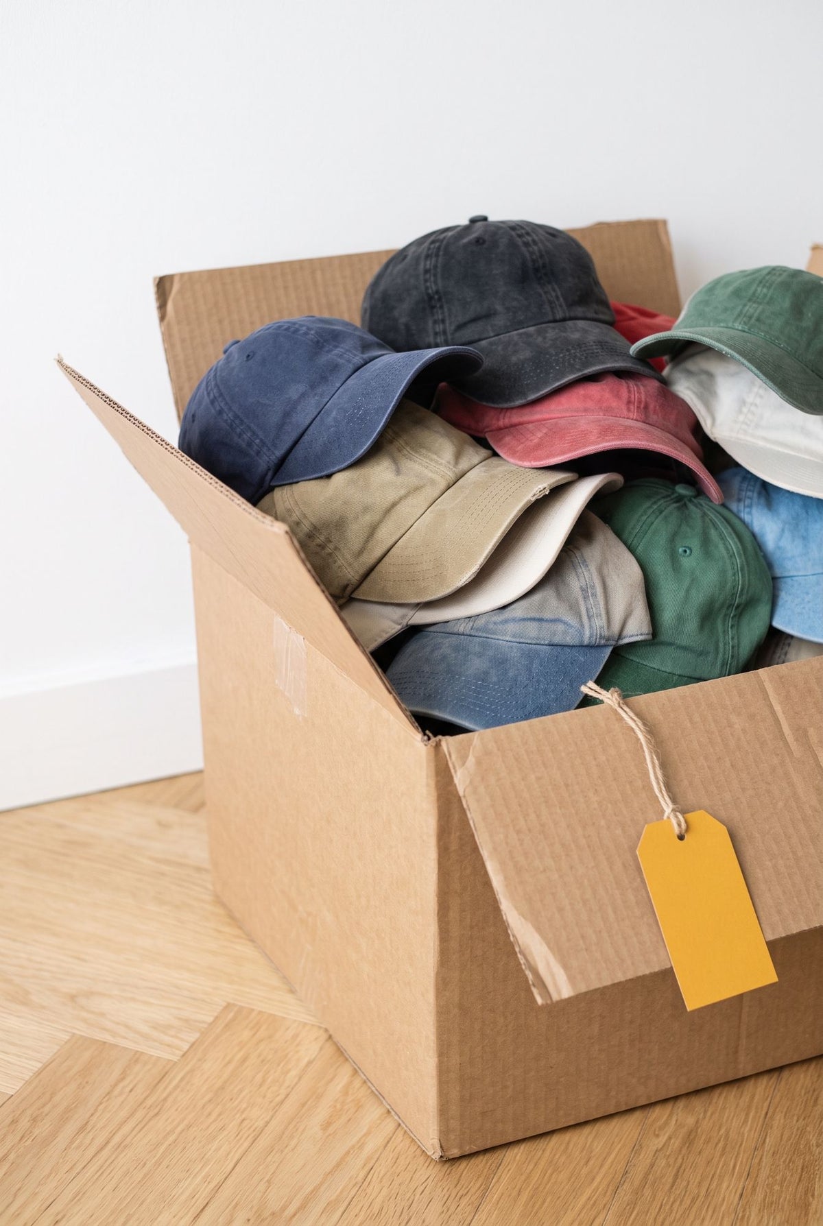 Casquettes vintage seconde main empilées dans un carton : variété de visières, modèles et coloris pour revendeurs